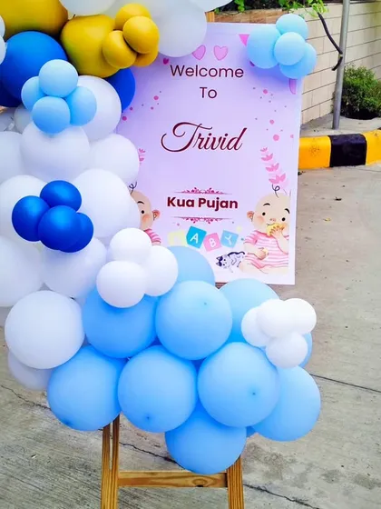 A personalized welcome sign for Trivid's Kuan Pujan ceremony. The sign is placed on an easel and decorated with a lovely blue, white, and yellow balloon arrangement.