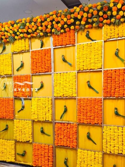 This vibrant backdrop for a mature function uses a grid design filled with yellow and orange marigolds. We added hanging parrot motifs in the alternating squares for a touch of traditional charm.