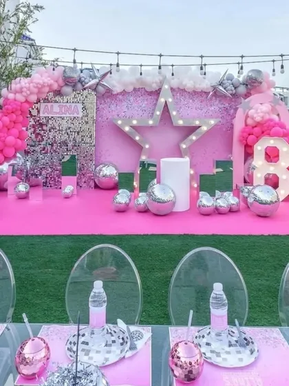 Another view of the Barbie Disco theme, showing the full stage setup on an outdoor lawn with themed table settings in the foreground.