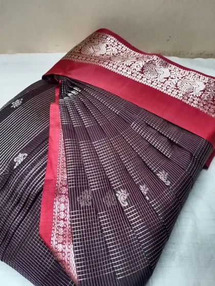 A unique black saree with red border and silver stripes, pleated neatly.