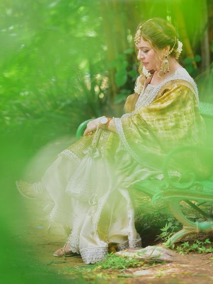 A duplicate of a previous image, this creative shot uses a green foreground blur for a dreamy effect, focusing on her serene expression in a beautiful lehenga.