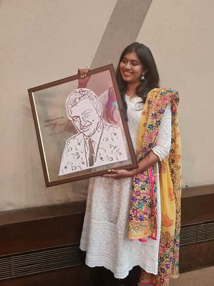 Me holding the finished and framed portrait of Madan Mohan. I added a floral pattern to his suit to give the piece an extra artistic touch.