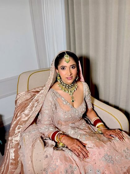 A full-length shot showing the bride's complete, elegant look. The makeup perfectly complements her stunning pastel lehenga.