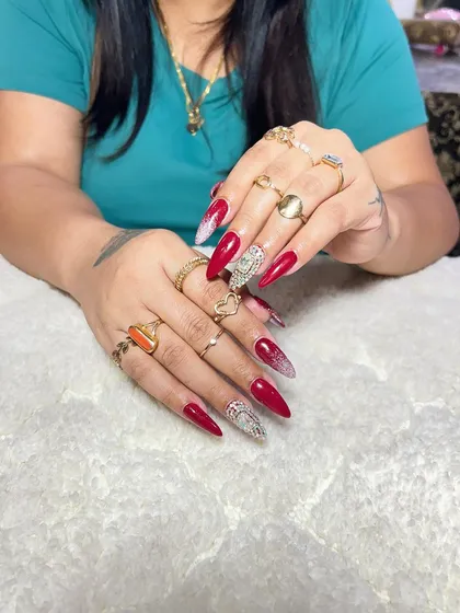 A bold and glamorous set of stiletto extensions. The design features a mix of deep red, snakeskin print, and a fully crystallized accent nail.
