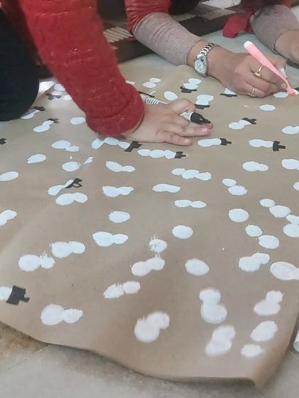Teamwork makes the dream work! Here, we are adding the finishing touches to our handmade snowman wrapping paper, a highlight of our Christmas workshop.