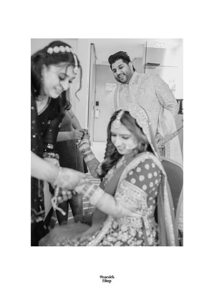 A candid black and white shot of the groom peeking in with a smile as the bride gets her final touches. A sweet, unscripted moment.