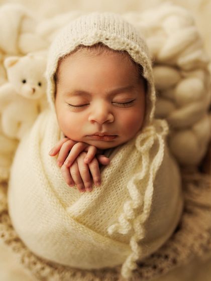 A close-up of this adorable setup, showing the delicate knit bonnet and the peaceful expression of the sleeping baby.