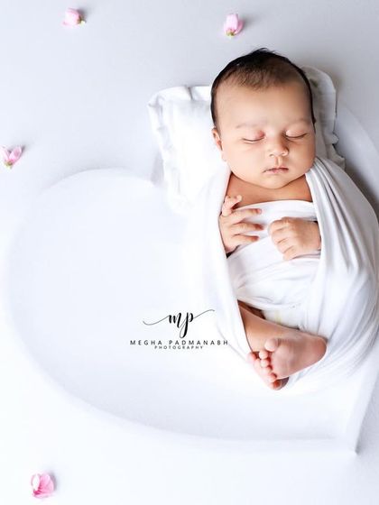 Another angle of the baby in the heart prop with pink petals, creating a soft and dreamy feel.