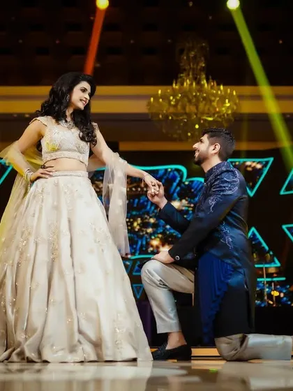 The groom proposes to his bride on stage during their reception, a beautiful and theatrical moment.