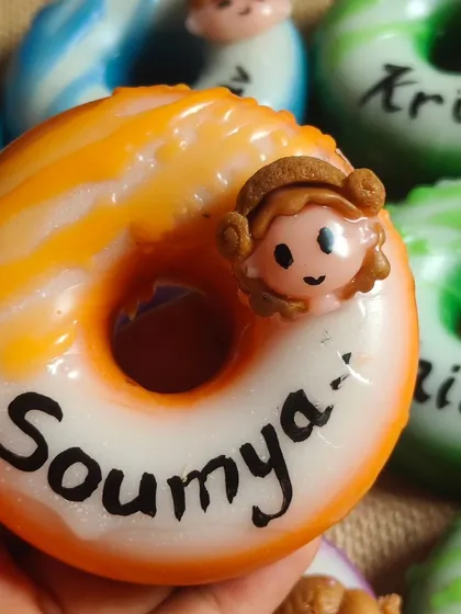 My personalized donut soaps are a huge hit for birthday return favors. This close-up shows a custom goat milk soap with the name "Soumya," handcrafted to be a sweet and memorable party gift.