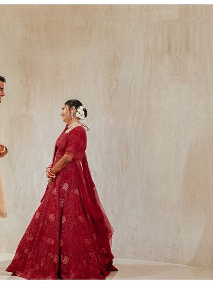 The first look. Katyayni and Kunal stand together, sharing their first moment on their wedding day. The minimalist background keeps the focus entirely on their connection.
