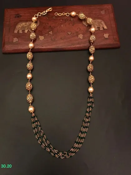 This multi-strand necklace combines black beads with pearl-like beads and golden accents. It's a classic and versatile piece that can be styled in many ways.