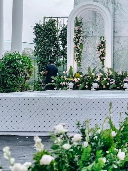 A closer look at the details of our modern reception stage. We use a mix of ferns and soft florals to create texture and depth, with subtle uplighting to highlight the architectural elements.