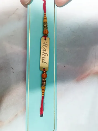 A closer look at the craftsmanship of the personalized metal name Rakhi.