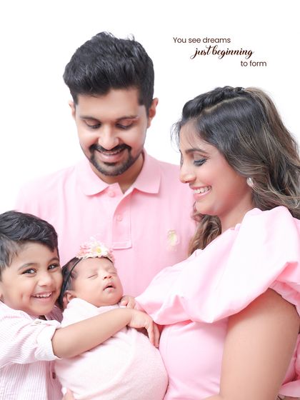 A complete family portrait, glowing with happiness. The older brother's charming smile next to his sleeping baby sister, all surrounded by their parents, makes for a heartwarming and precious memory.