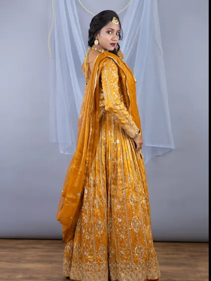 The back view of the mustard lehenga, showing the elegant drape of the dupatta and the detailed embroidery on the sleeves.