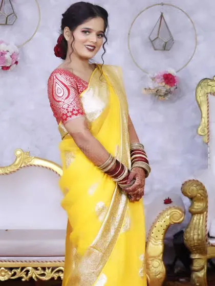 A full-length view of the bride, showing the elegant drape of her yellow saree and the beautiful stage decor.