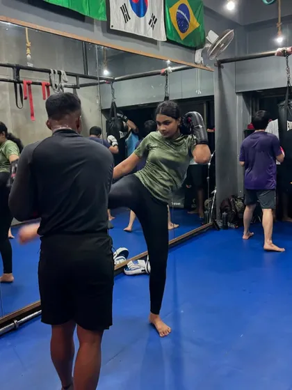 Here, I am guiding a client through kickboxing drills, focusing on proper form for a high kick. I provide one-on-one attention even in group settings to ensure everyone masters the technique for power and safety.