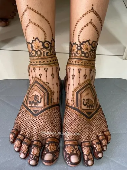 This delicate bridal feet design features a net pattern across the foot, with a small elephant motif and lotus details on the toes.