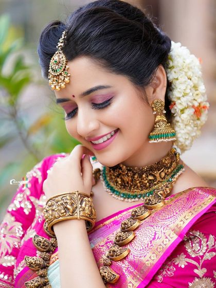 A soft and delicate portrait of Ashika Ranganath, with a focus on her happy expression and the fine details of her makeup.