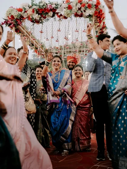 The bride's entrance is pure energy and joy. Here, she is surrounded by smiling family under a beautiful floral canopy. I focus on capturing these high-energy, celebratory moments that define a Maharashtrian wedding procession.