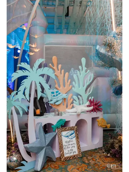 A styled corner with pastel-colored props, including palm trees and coral, creating a playful and imaginative photo opportunity.