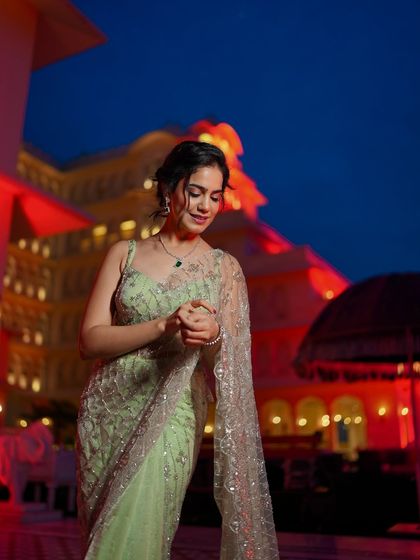 A candid shot in my pastel green saree against a beautifully lit palace at night.