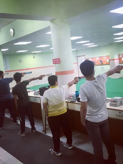 Shooters practicing their 10m air pistol technique, focusing on their stance and arm extension.