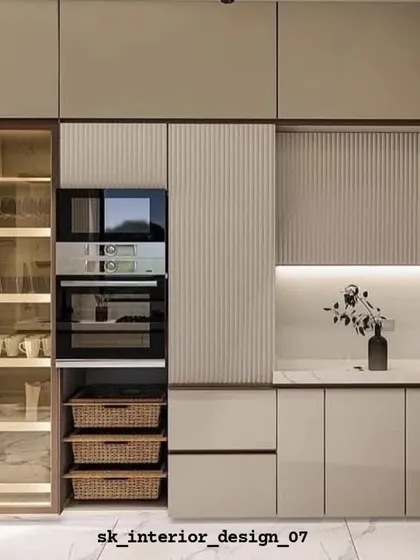 A kitchen that excels in storage, featuring a tall pantry unit, built-in ovens, and deep wicker baskets. The fluted panel detail adds a modern textural element.