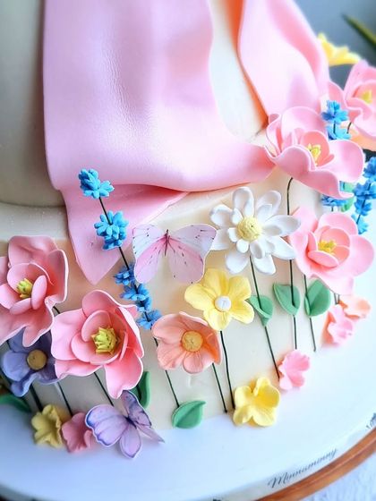 A close-up of the delicate, multi-colored sugar flowers at the base of the cake.