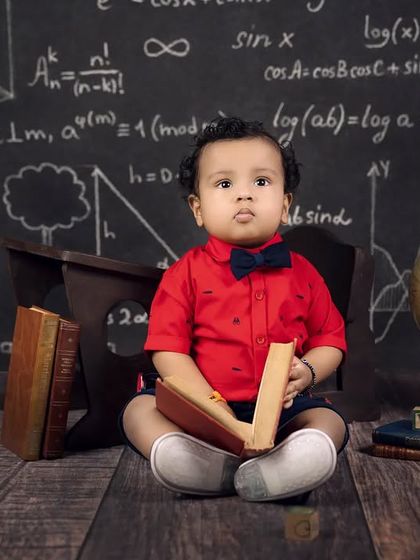 Another little scholar, "Rudra," sits with a book in his classroom-themed photoshoot.