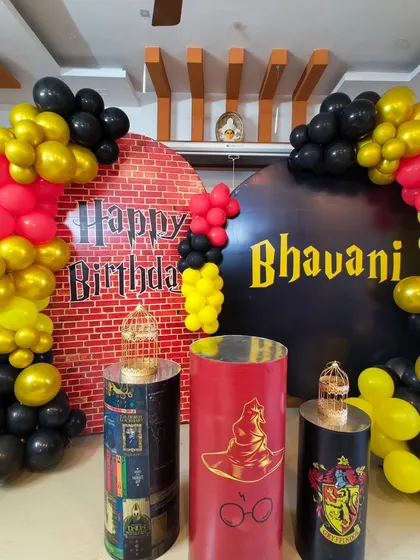 A magical Harry Potter themed birthday party setup. We used the signature house colors of red, gold, and black for the balloon arch, a custom brick wall backdrop, and themed pedestals featuring the sorting hat and house crests.