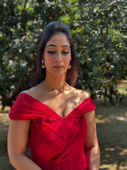 A close-up of the red dress look, highlighting the winged liner and the natural, glowing skin finish.