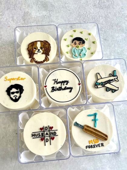 A set of seven mini bento cakes, each with a different flavour and a design that tells a story about the birthday person.