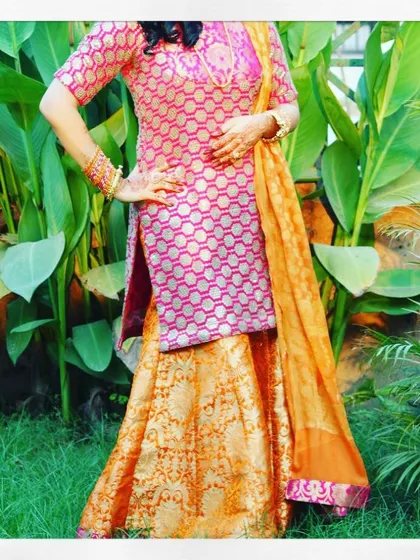 For festive occasions like Diwali, I design vibrant traditional wear like this sharara suit. This outfit features a pink brocade kurta paired with a contrasting orange brocade sharara and a matching dupatta, making it a complete and celebratory ensemble.