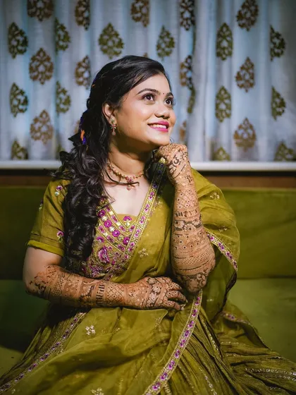 A lovely candid portrait of the bride, lost in happy thoughts during her mehndi ceremony. The olive green of her lehenga beautifully complements the rich color of the henna.