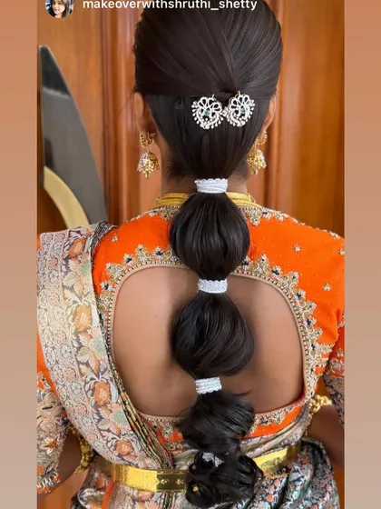 A modern and chic bubble ponytail, perfect for a Sangeet or reception. This sleek style is accented with a beautiful kundan hair clip, offering a contemporary twist on bridal hair.