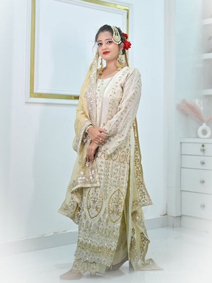 A classic pose in an ivory sharara suit, showing the full outfit and the way the jewellery complements the silver and gold embroidery.