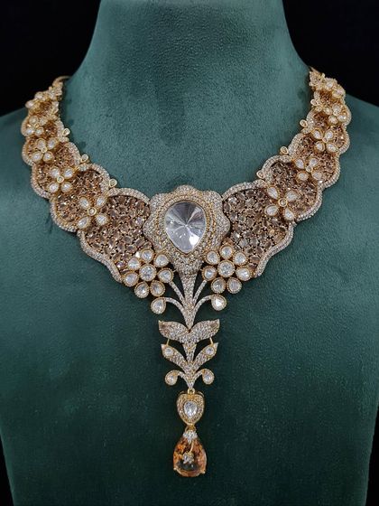 A grand bridal necklace with a large uncut stone and intricate gold-toned filigree work. This piece blends traditional motifs with a modern silhouette for a stunning effect.