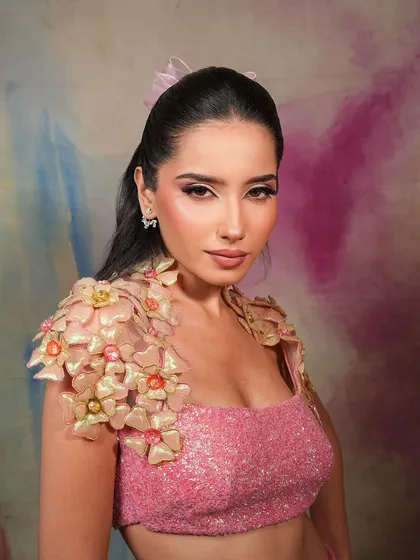 A fun and flirty look with a pink sequined top and 3D floral details. The makeup is soft and pretty, with a focus on a winged liner and glowing skin.