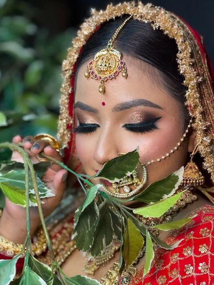 An artistic shot showcasing a classic bridal eye makeup with a winged liner and gold glitter. The use of props like leaves can add a creative touch to your portfolio.