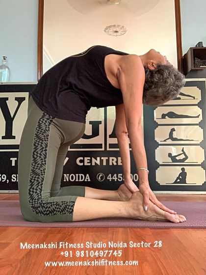 A slightly different angle of Camel Pose, showing the hands reaching for the heels to support the backbend.
