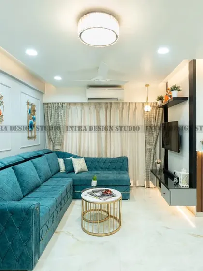 A look at a complete living room we designed, blending comfort and modern style. The vibrant teal L-shaped sofa, custom TV unit, and open-concept layout leading to the breakfast bar create a welcoming and cohesive family space.
