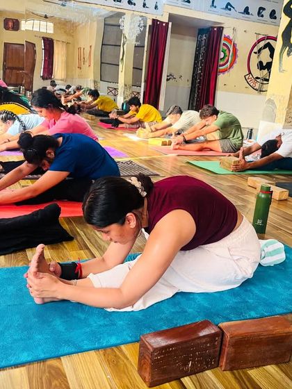 Students engage in Paschimottanasana (Seated Forward Bend). We use props like blocks to help everyone access the pose, regardless of their flexibility level.