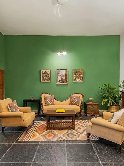 The living area of the Arundati suite, featuring a vibrant green wall, antique furniture, and traditional Indian art, perfect for relaxed family portraits.
