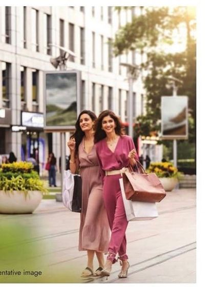 A lifestyle shopping scene styled for a DLF campaign. The coordinated, chic jumpsuits on the models create a fashionable and aspirational image of a day out, enhancing the location's appeal as a retail destination.