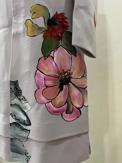 A detail of the floral artwork on the sleeve and side of the custom sherwani. The combination of different flower types and colors creates a rich, botanical design.