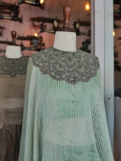 This flowing cape in a soft, textured green is defined by its stunning, heavily beaded collar. It's an effortlessly festive piece that is sure to turn heads.