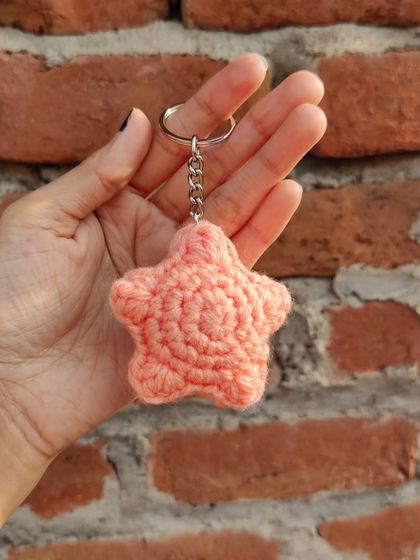 Puffy star-shaped keychains, available in pastel colors like lavender and peach, with an optional pearl strap.