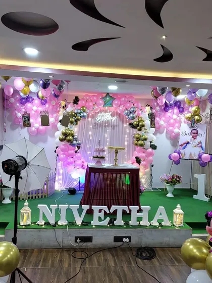 A classic pink and purple first birthday party with Minnie Mouse accents. The full stage setup includes a beautiful balloon backdrop, marquee letters, and personalized photo displays.